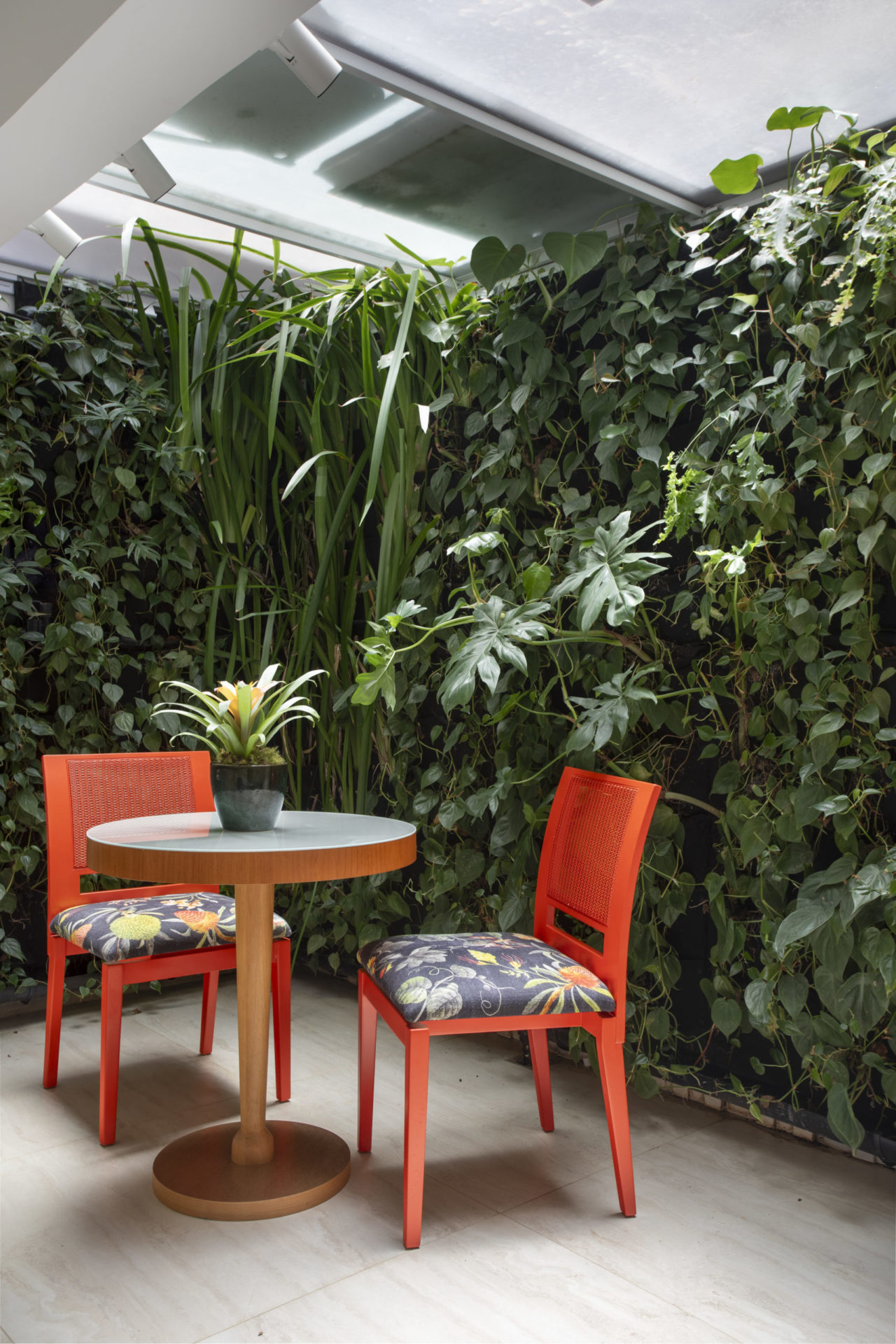 Uma parede verde, uma mesinha e duas cadeiras laranjas, no espçao da cozinha e da área de serviço.