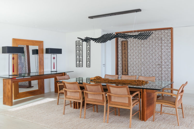Ambiente da sala de jantar decorado em tons neutros, e a resença da madeira na mesa, cadeiras e aparador.