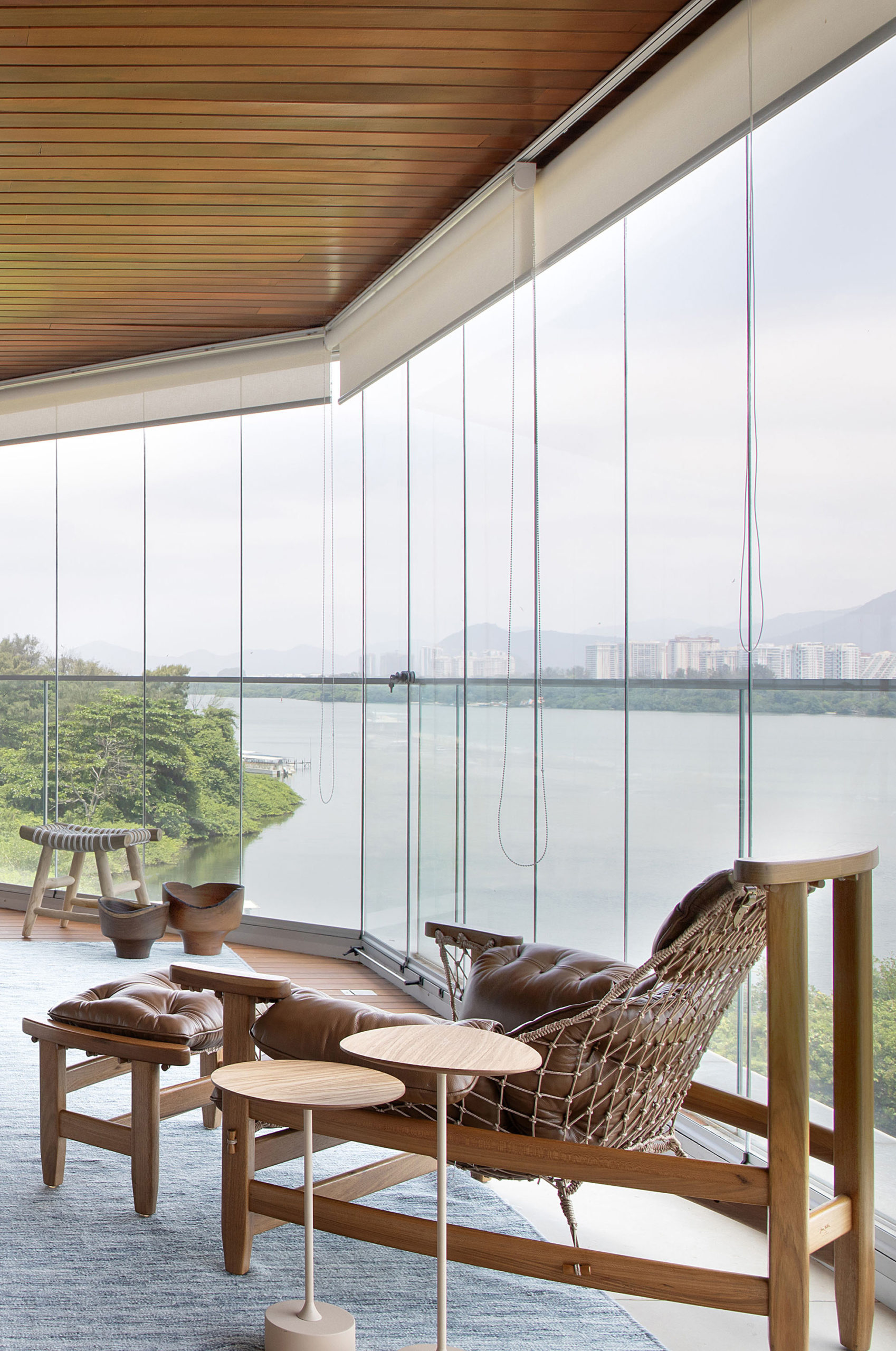 Varanda fechada com cortina de vidro, tem a vitsa da lagoa de Marapendo no RJ. Mobiliada com móveis de design brasileiro