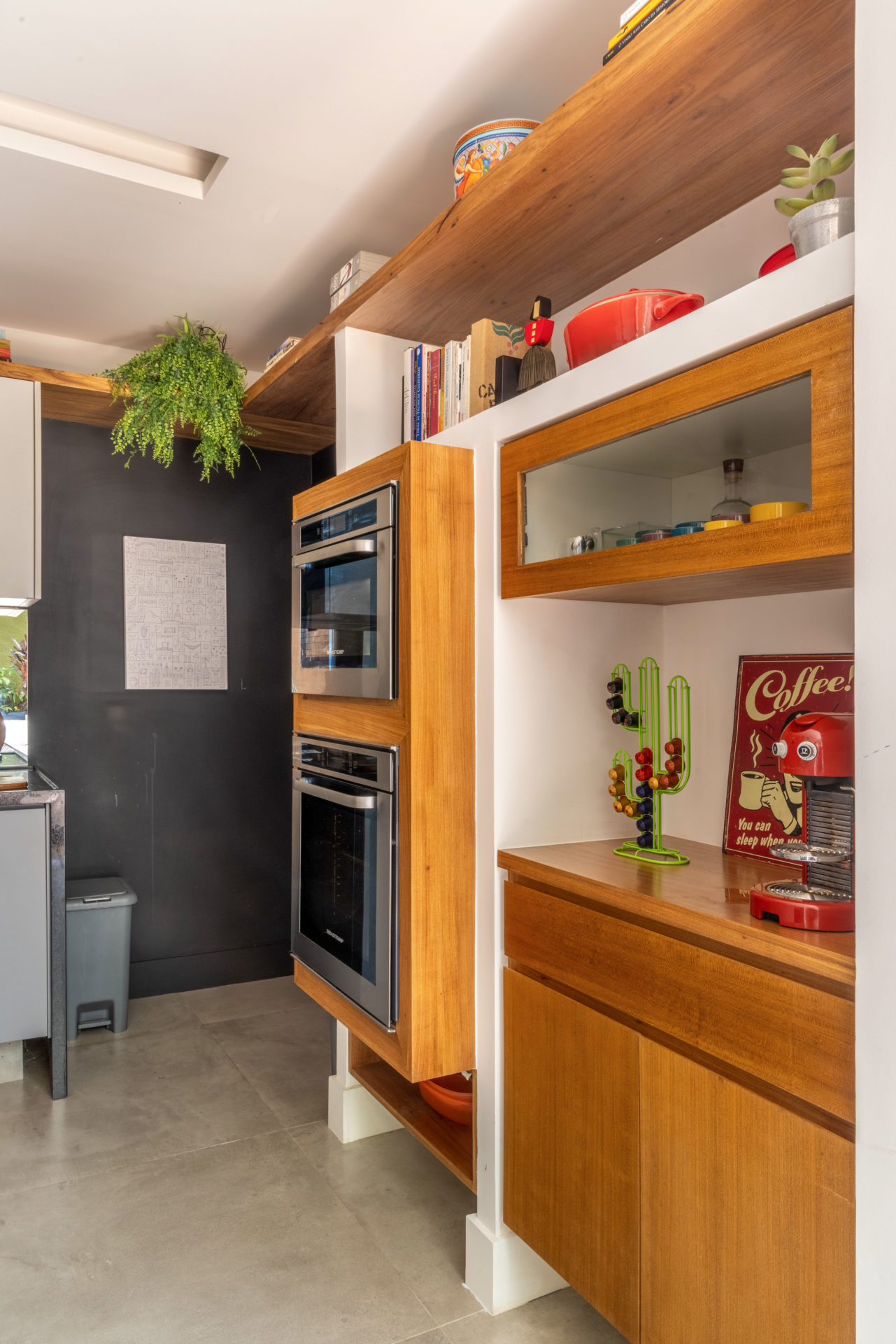 cozinha e a sala integradas ao pátio, foram projetadas para serem pontos de convívio, onde moradores e visitantes podem reunir-se confortavelmente, promovendo um senso de comunidade. Cozinha clara, com luz natural. Torre de equipamentos em um nicho de madeira