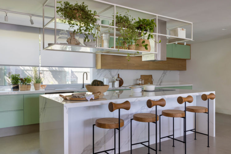 Cozinha integrada a sala, armários em verde água e branco. Ilha central com banquetas alta de design assinado 