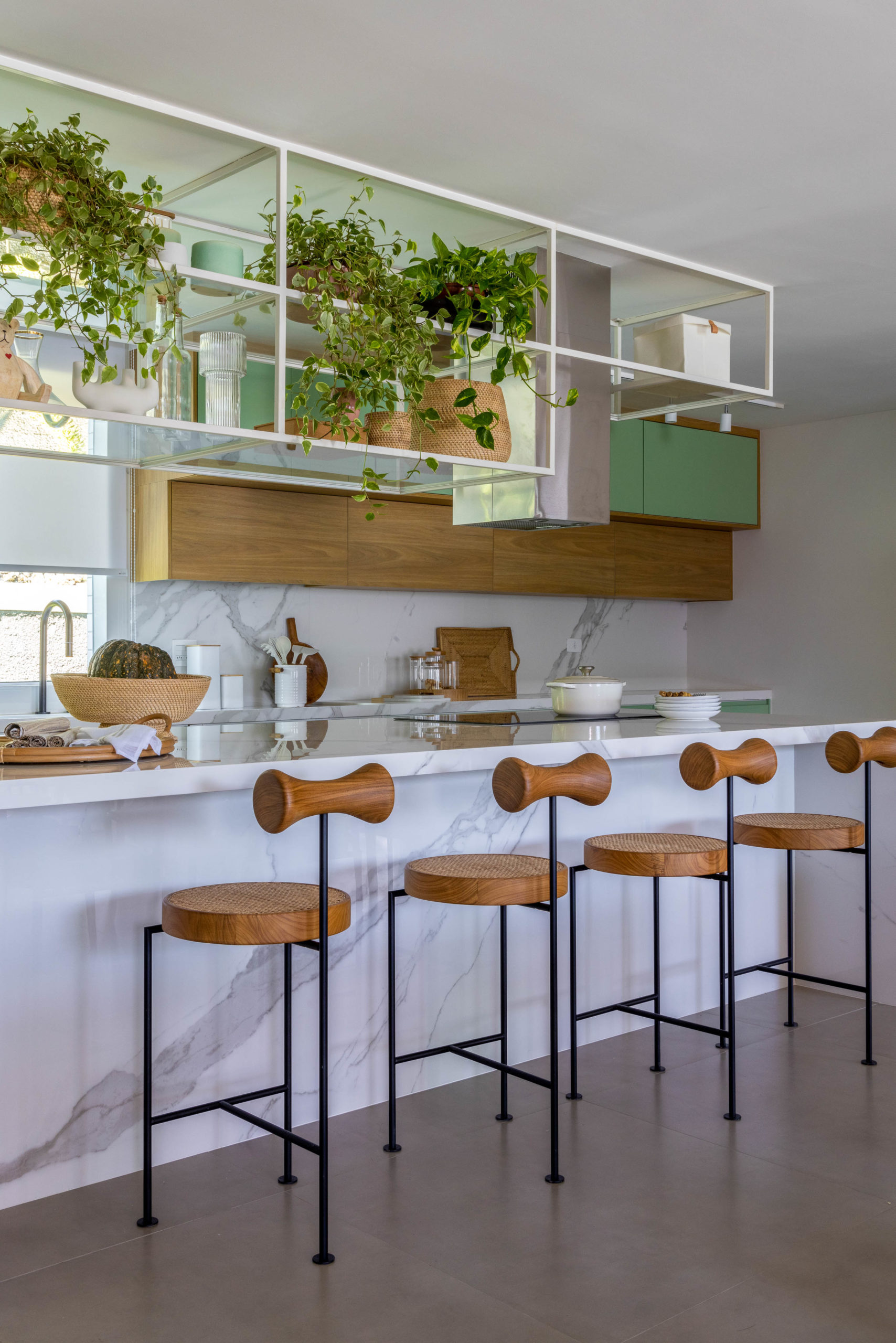 Cozinha integrada a sala, com balcão alto e banquetas de design assinado