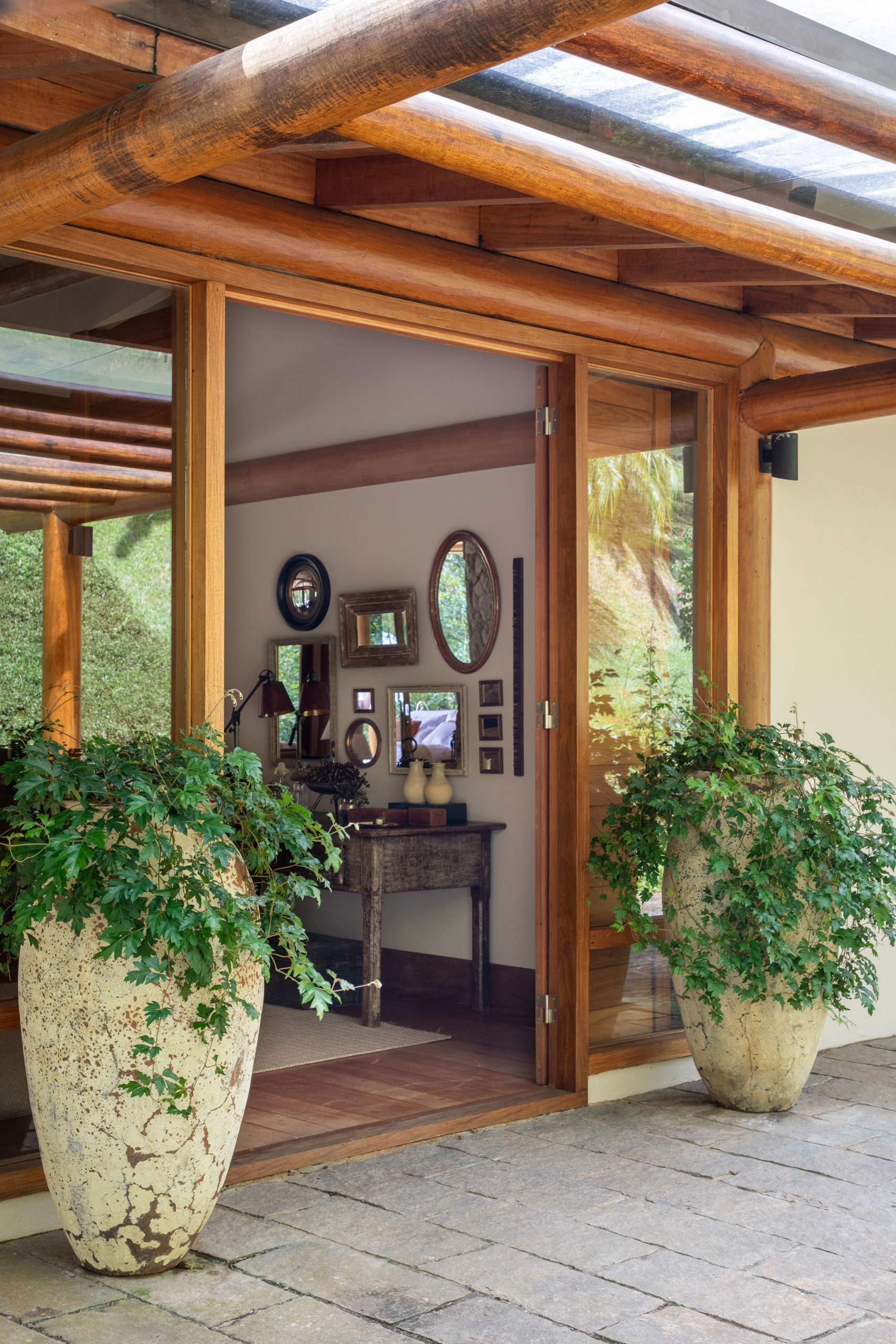 Entrada de uma casa de campo, com dois vasos grandes na lateral da porta.