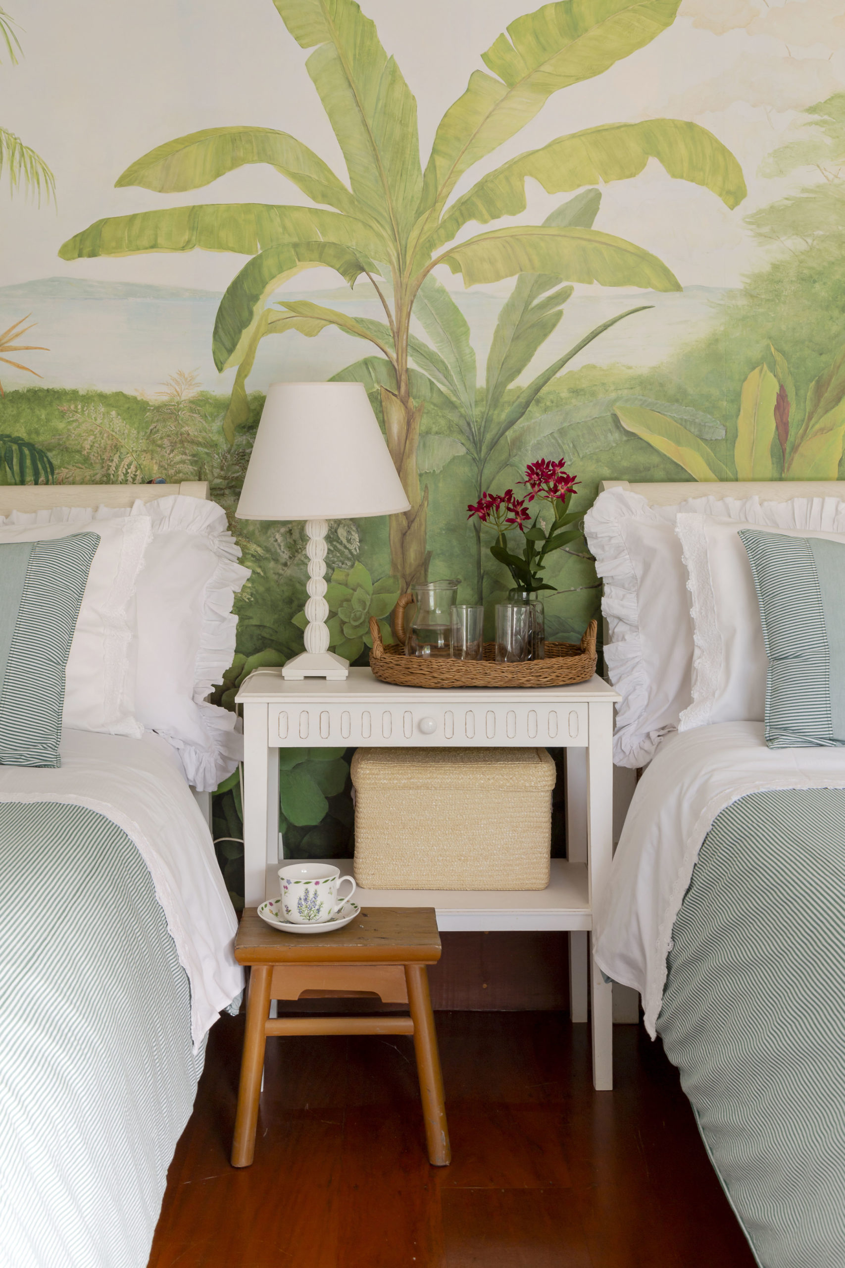 Quarto de hóspede em uma casa de campo, decorado com papel de parede com desenhos, bananeiras e mata tropical. 