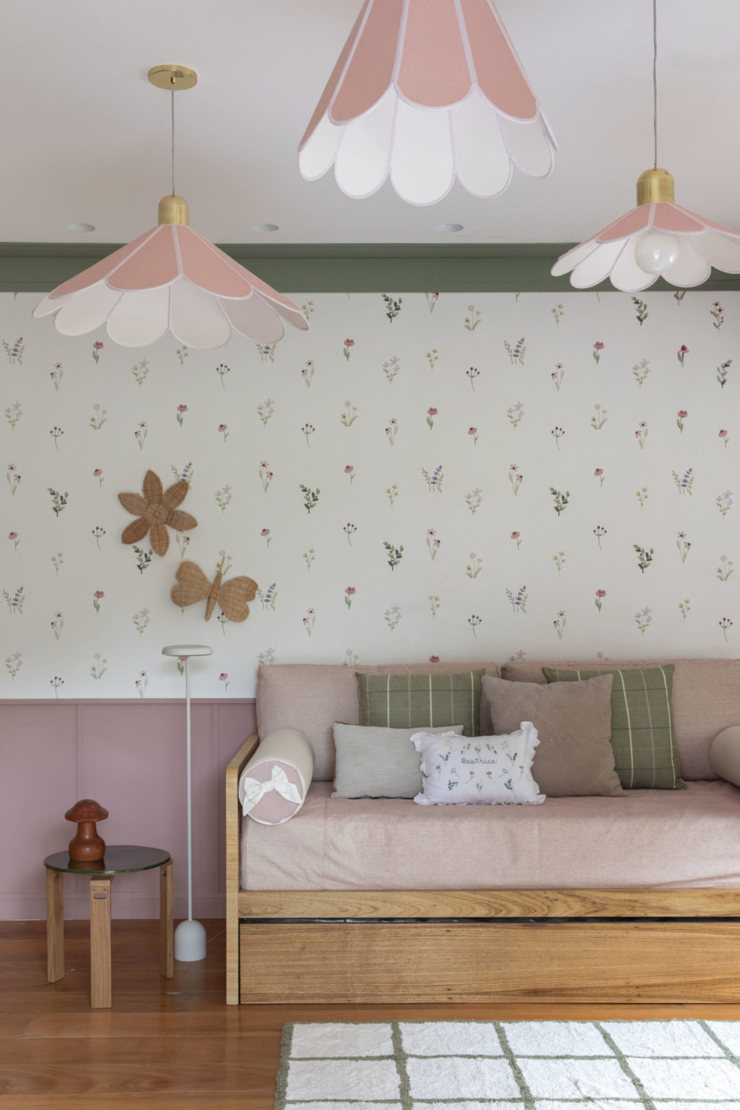 Quarto de bebê menina, decorado com papel de parede de florzinha e três luminárias pendentes em forma de flor 