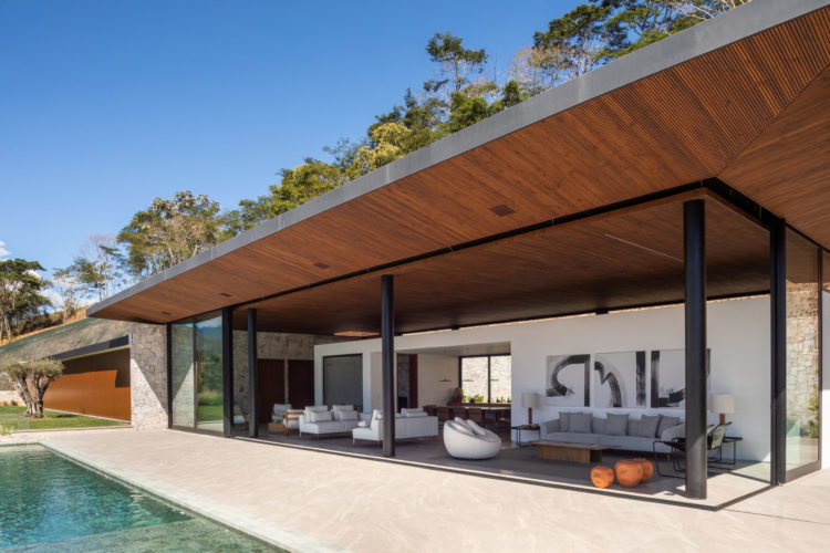 Localizada em Itaipava (distrito de Petrópolis, RJ), esta casa foi construída a partir de uma estrutura metálica aparente pintada de preto, com forro do teto em ripas de Pinus tonalizado e fachadas ora em esquadrias piso-teto de alumínio preto e vidro transparente (que permitem integrar os espaços internos com a área externa) ora em painéis articulados de alumínio ripado com pintura amadeirada, ora em pedra Moledo.