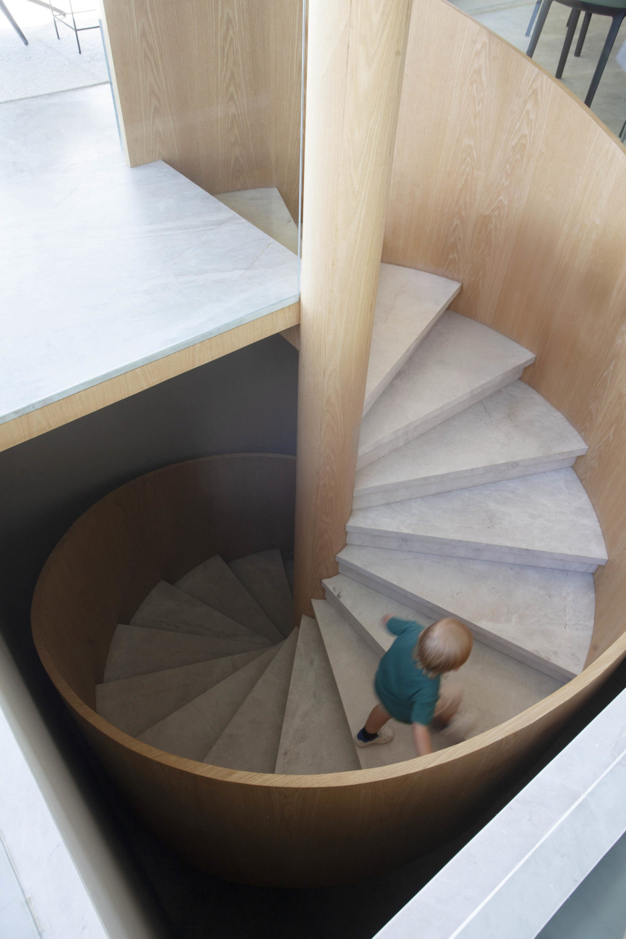 Escada espiral, com o guarda-corpo em madeira e os degraus em mármore