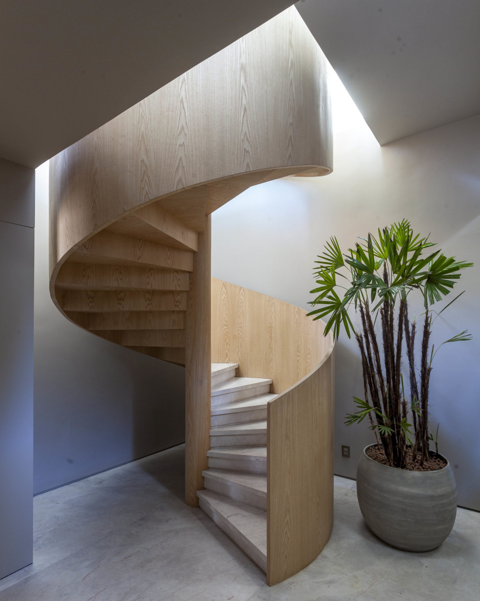 Escada espiral, com o guarda-corpo em madeira e os degraus em mármore
