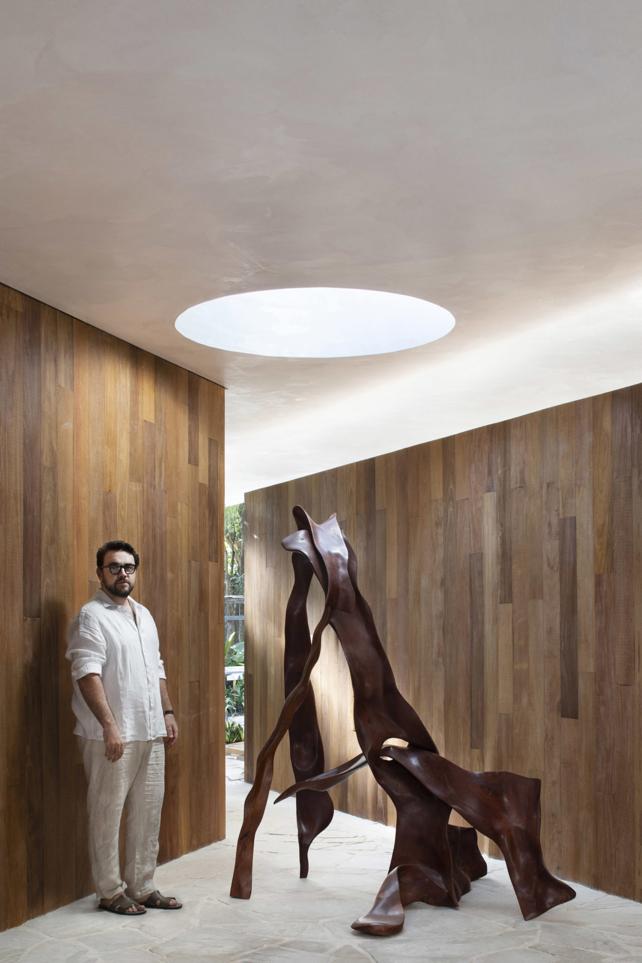 arquiteto ao lado de escultura de madeira