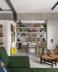 Visão na horizontal da sala de jantar e parcial da sala de estar com o sofá verde