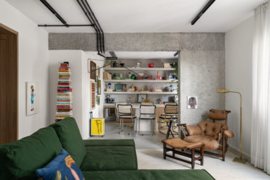Visão na horizontal da sala de jantar e parcial da sala de estar com o sofá verde