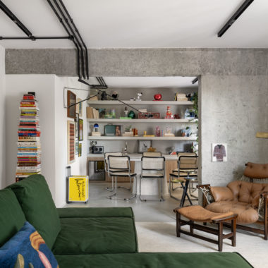 Visão na horizontal da sala de jantar e parcial da sala de estar com o sofá verde