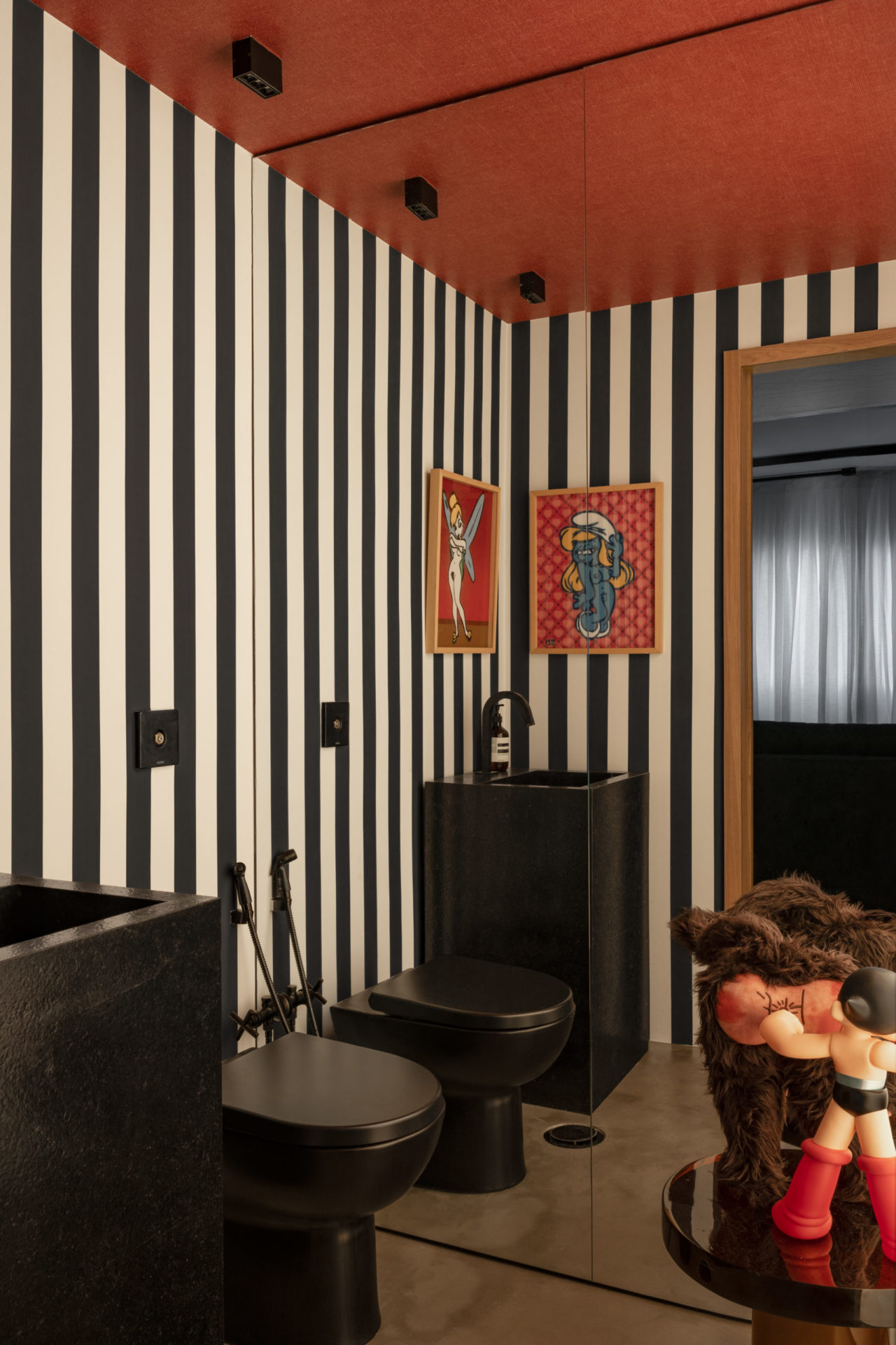 banheiro com paredes em listras, quadros pop arte com destaque na cor preta