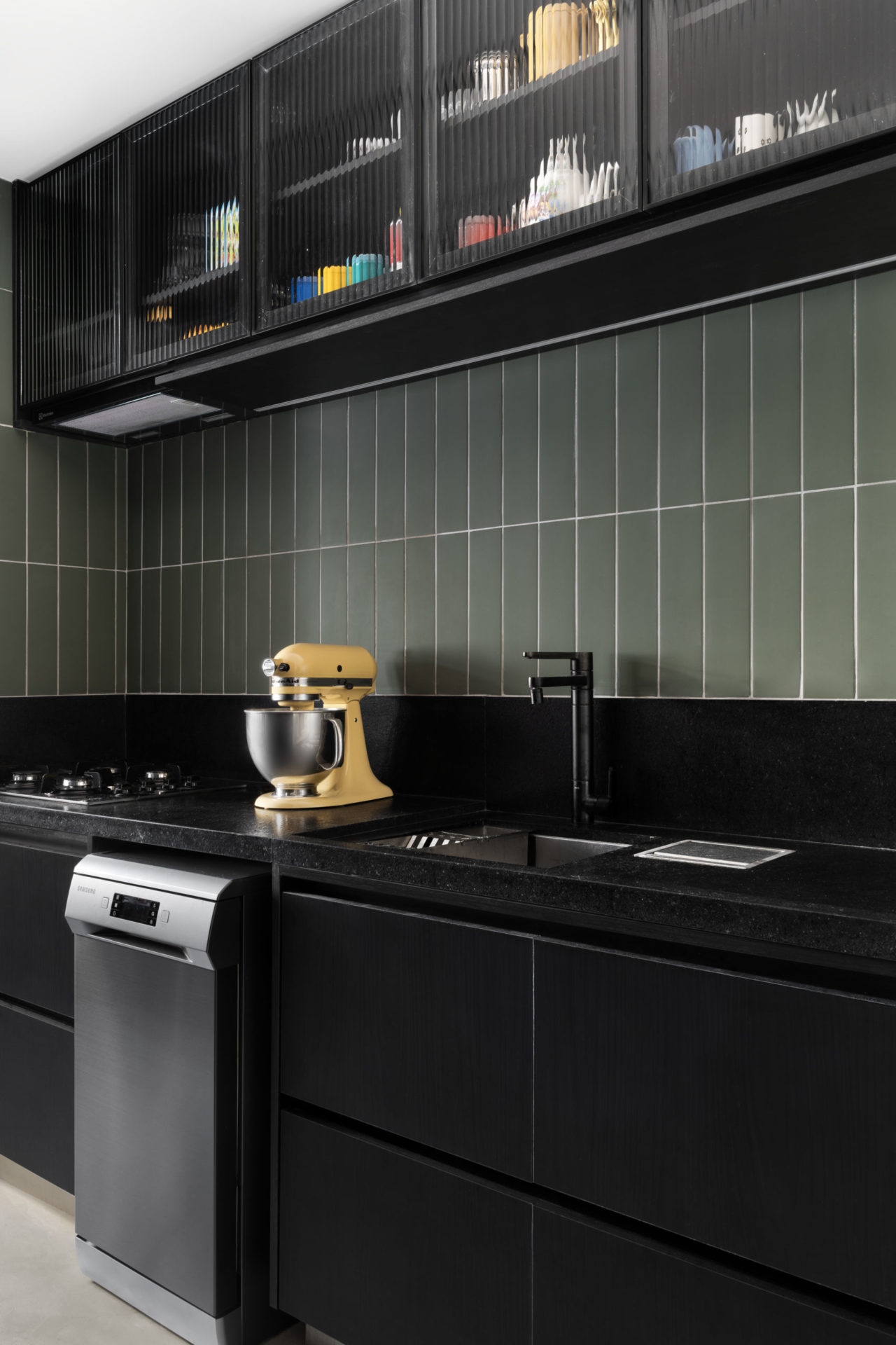 Cozinha com armários na cor preta, visual industrial e, na bancada, uma batedeira.
