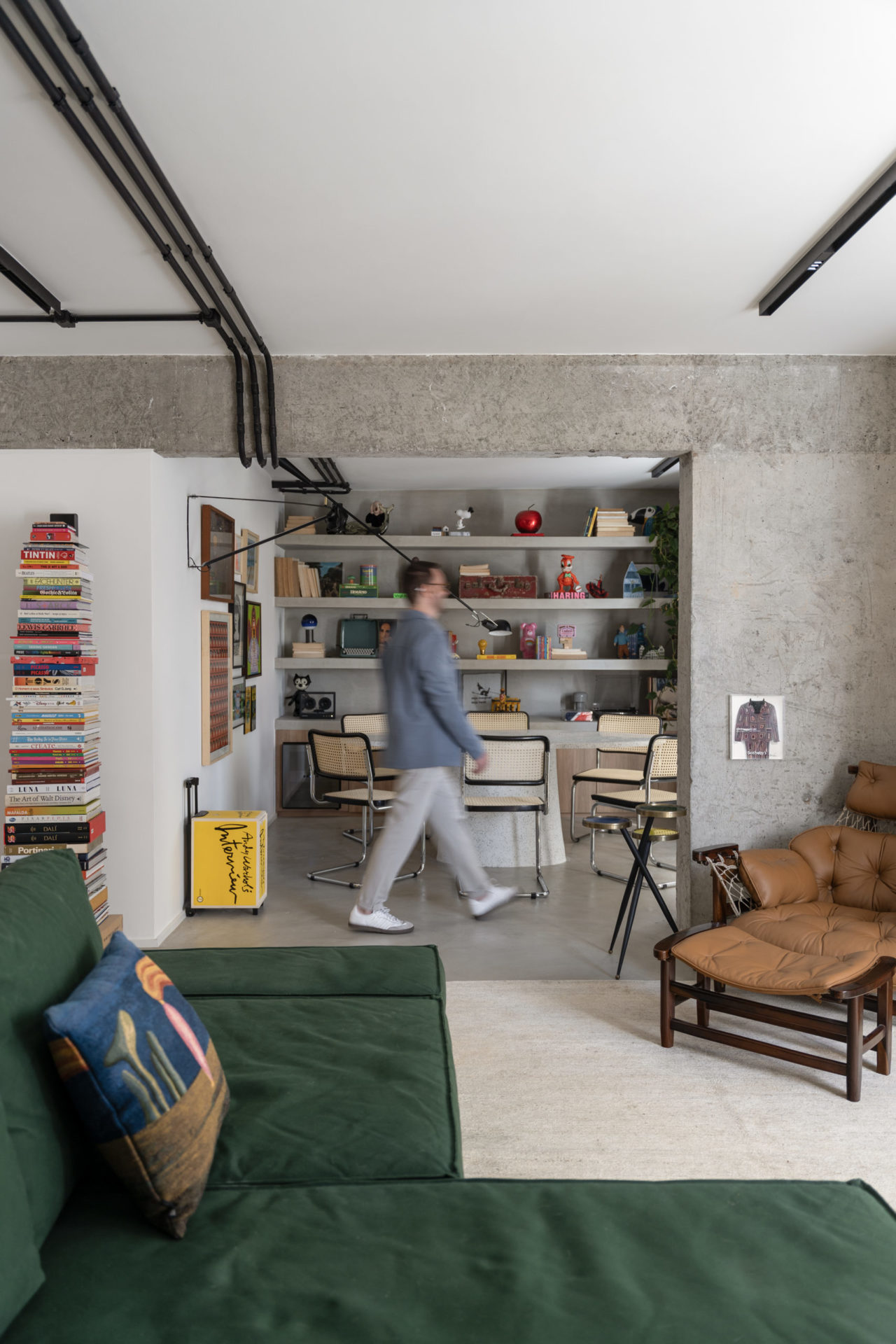 Visual da sala com livros, quadros, uma mesa de jantar e uma estante.