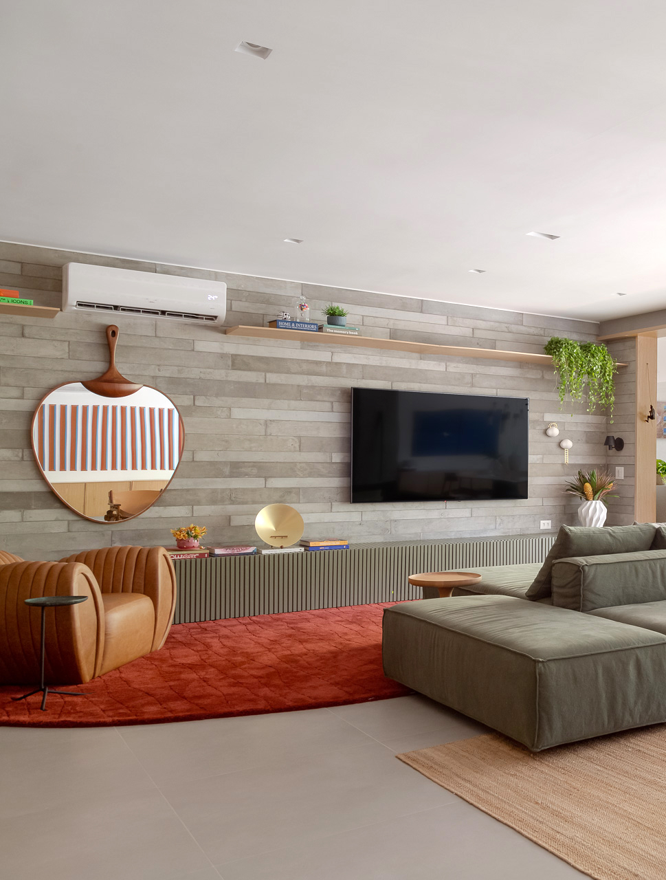 sala de tv com sofá cinza e poltrona de couro e espelho na parede