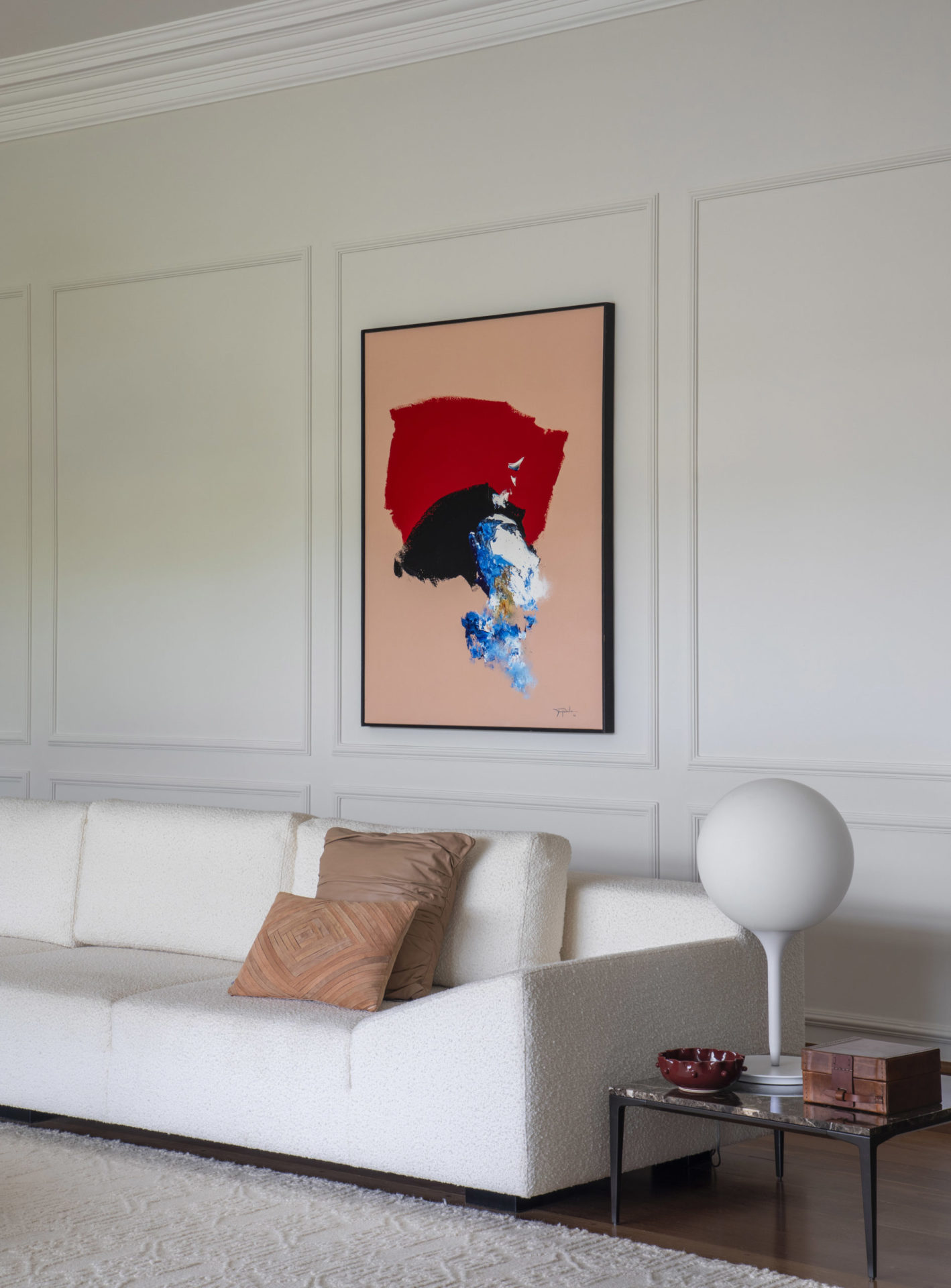 sofá branco e quadro em tons vermelho, azul, preto e salmon na parede