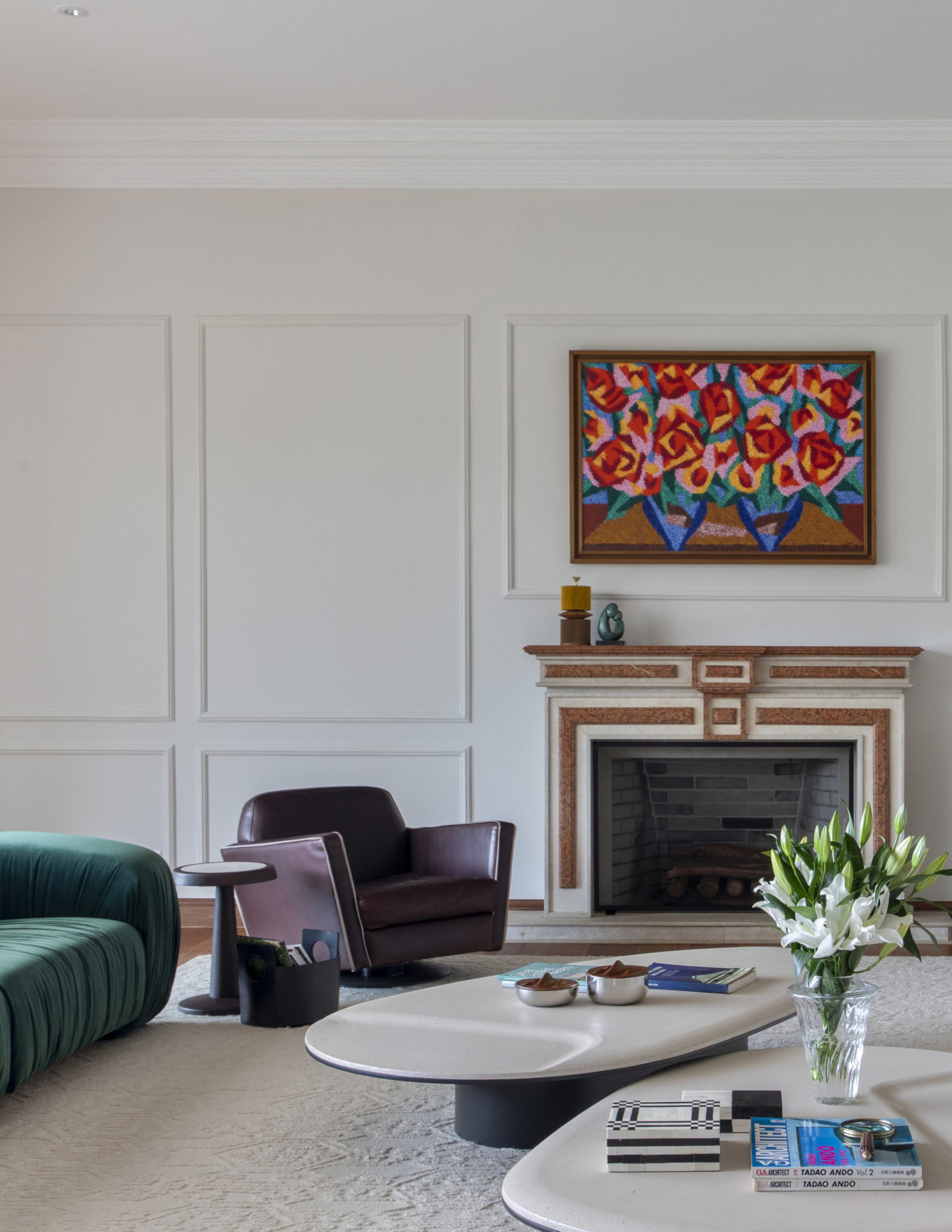 sala com poltrona, lareira e um quadro com flores acima da lareira