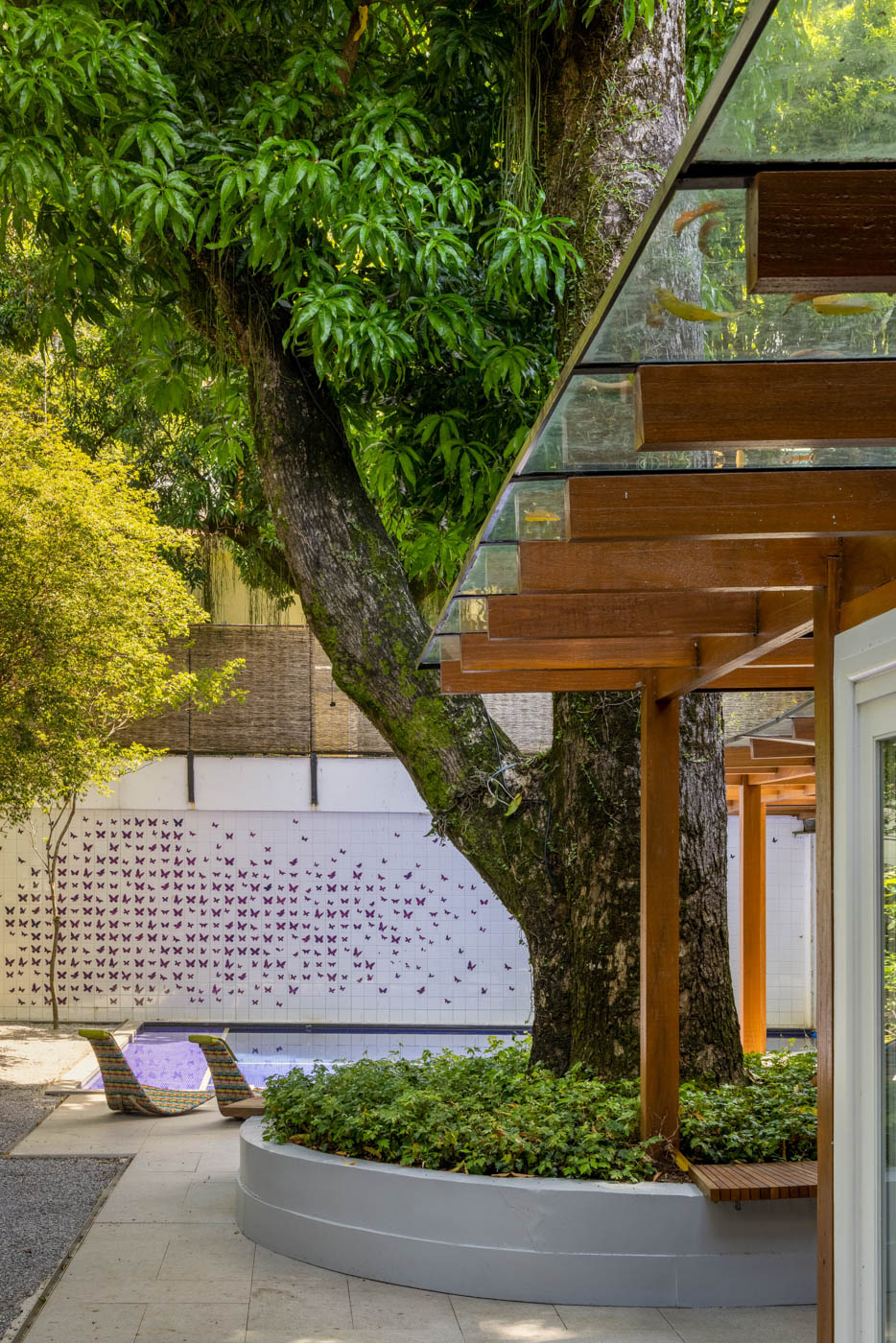 Área externa, de uma cada no Rio, na parede de fundo da piscina, azulejos criam um painel artístico.