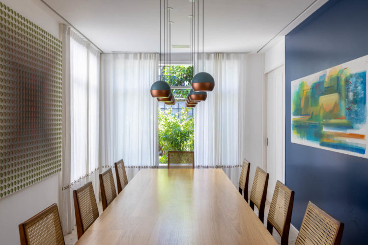 Sala de jantar com um das paredes laterais pintadas de azul.