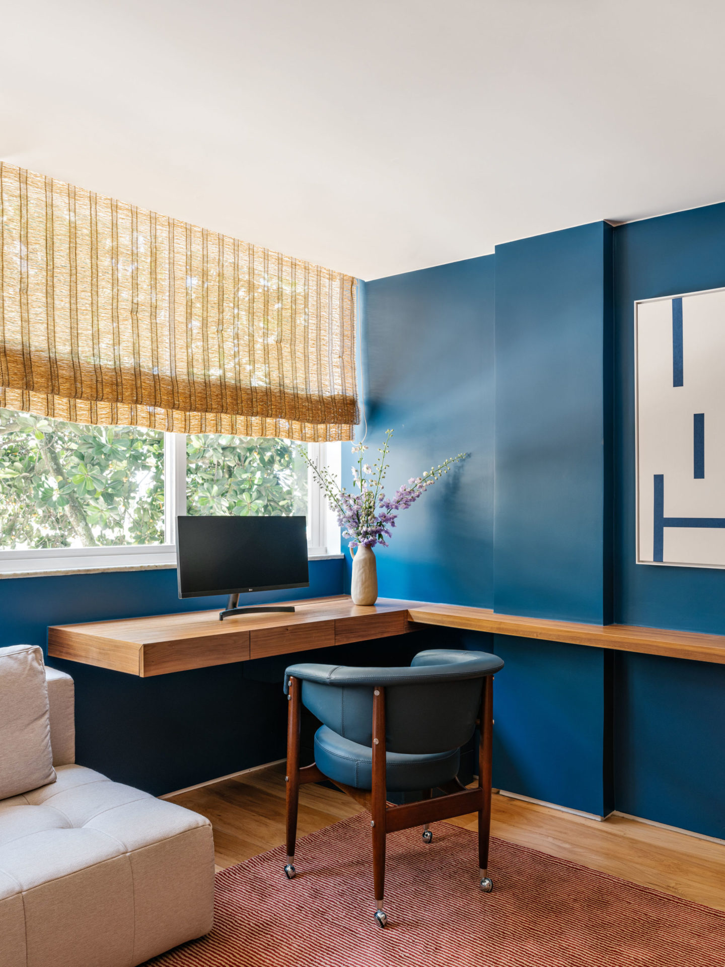 na foto escritório com mesa de madeira, parede azul e cadeira beg