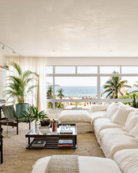 sala com uma janela grande, um sofá branco, mesa de centro e quadros na parede