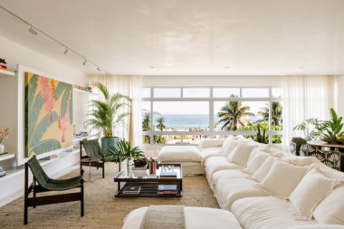 sala com uma janela grande, um sofá branco, mesa de centro e quadros na parede