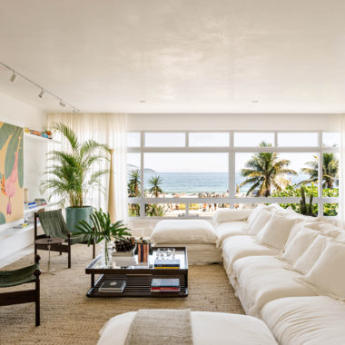 sala com uma janela grande, um sofá branco, mesa de centro e quadros na parede