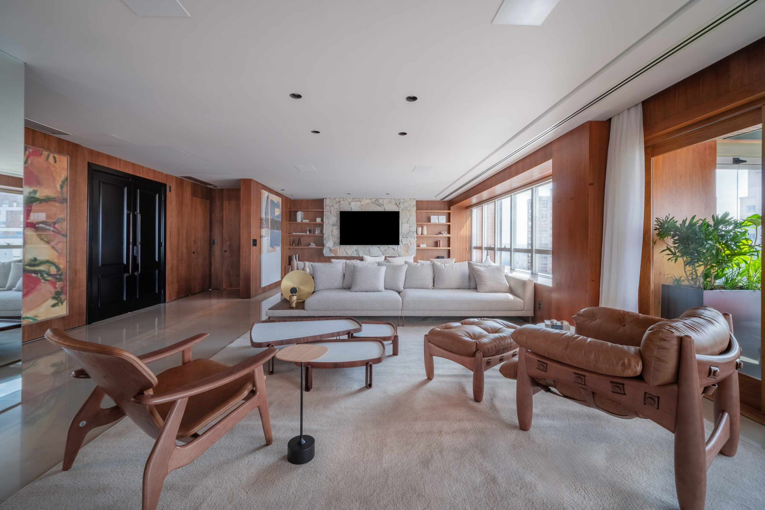 sala de estar com grande janela, TV, sofá branco, poltronas e mesa de centro