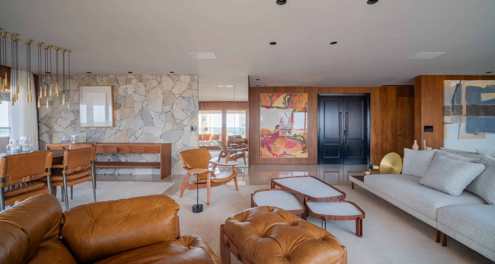 sala de estar com paredes em madeira, sofá, poltrona de couro