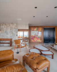 sala de estar com paredes em madeira, sofá, poltrona de couro