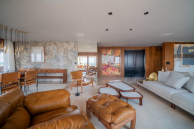 sala de estar com paredes em madeira, sofá, poltrona de couro