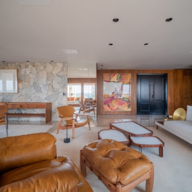 sala de estar com paredes em madeira, sofá, poltrona de couro