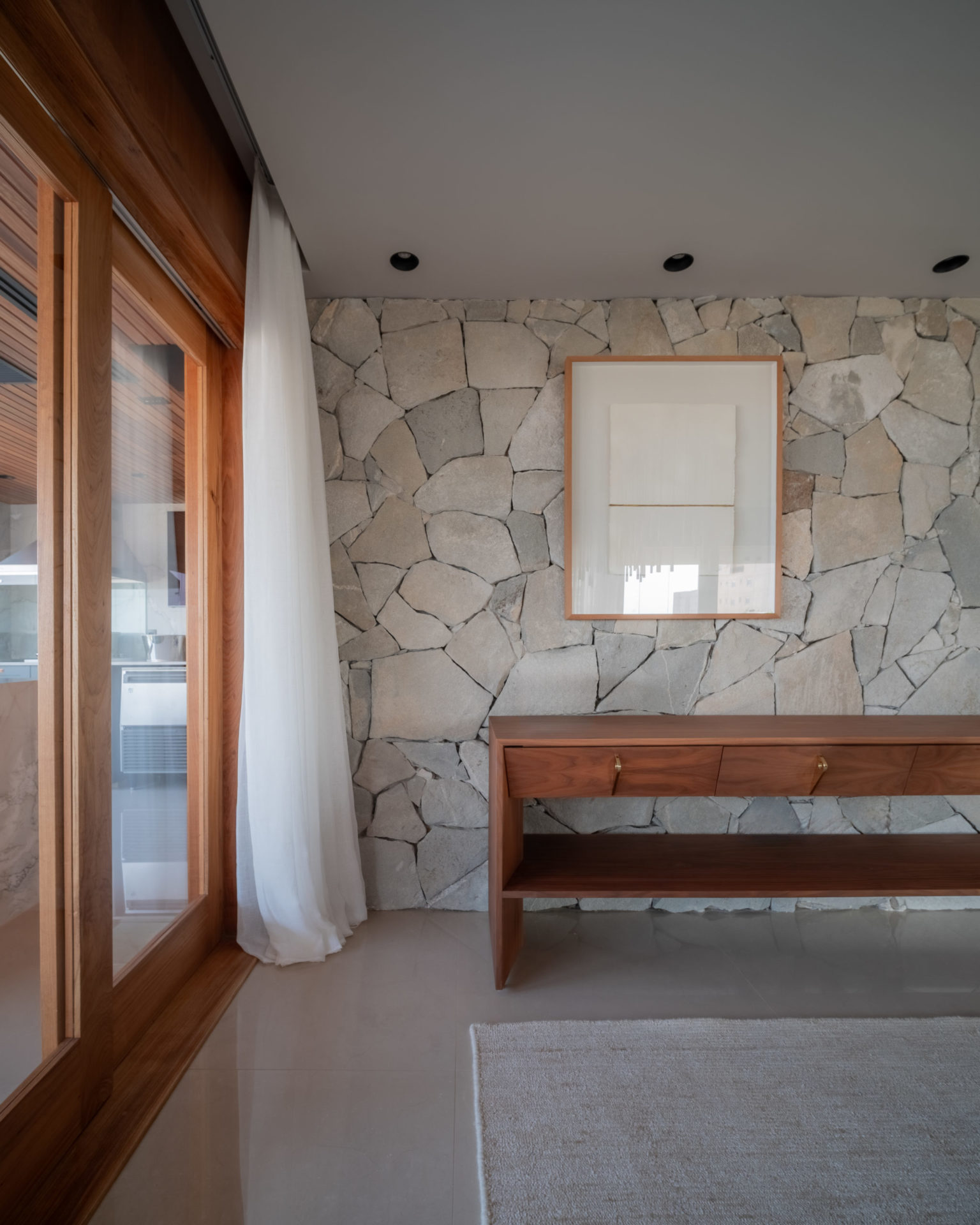 espaço entre sala e varanda com aparador de madeira e cortina branca