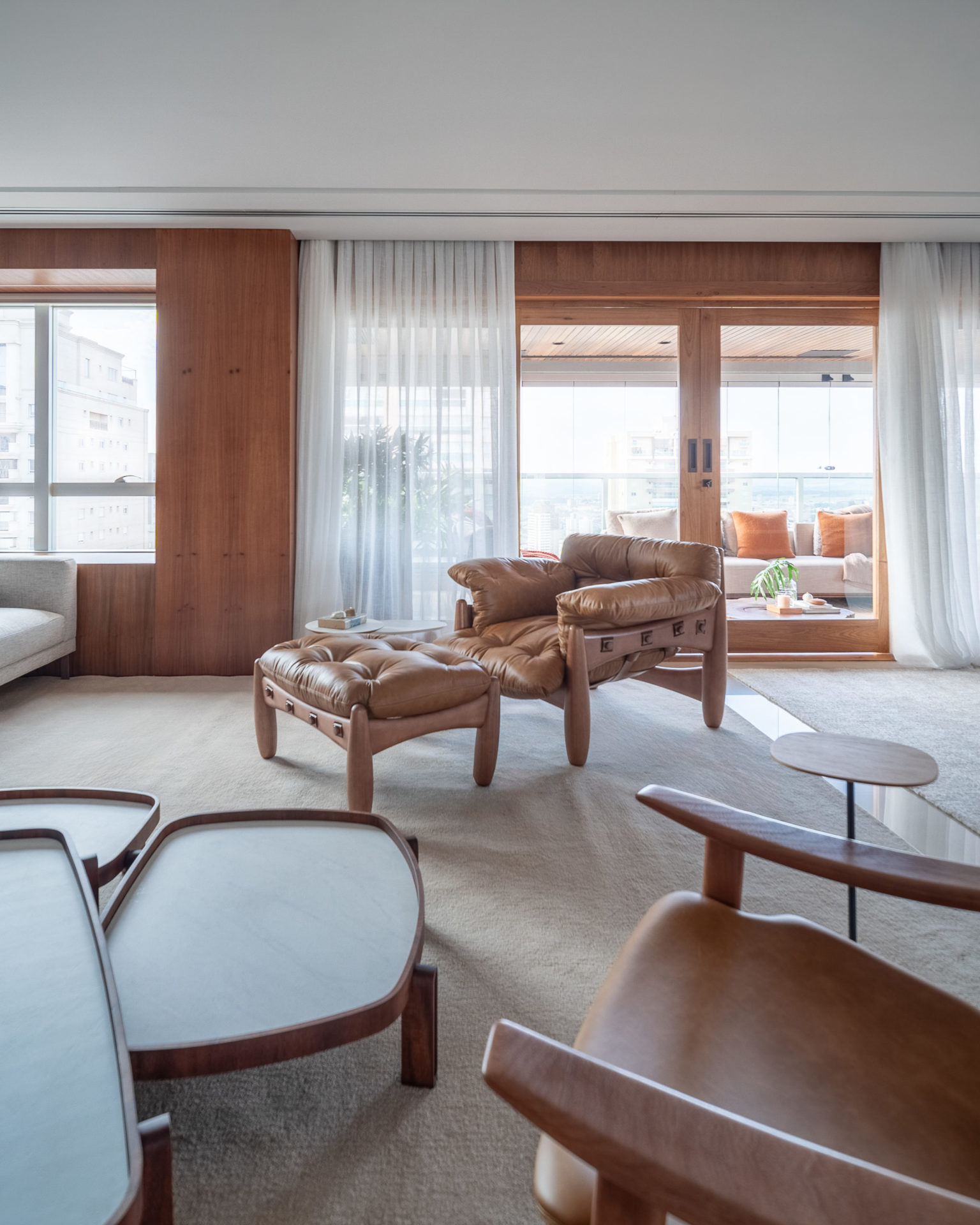 sala com janela e varanda, poltrona de couro e mesa de centro