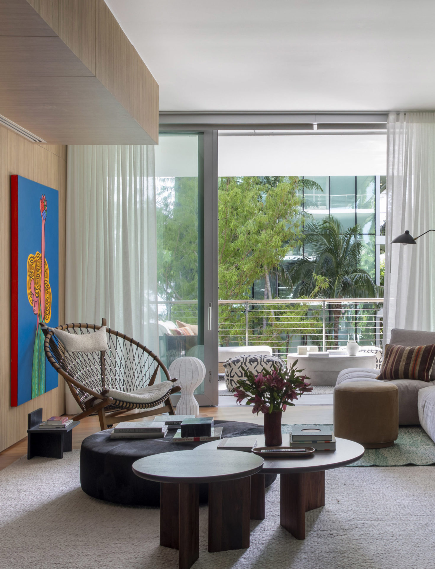 sala com poltrona, mesa de centro, sofá, varanda, cortina e quadro colorido