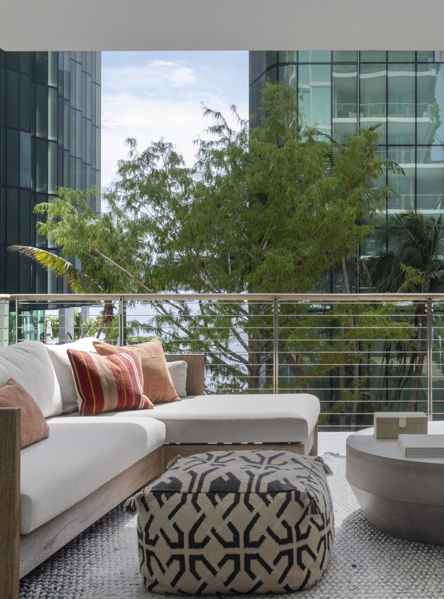 varanda com vista para outros prédios e sofá ilha com almofadas