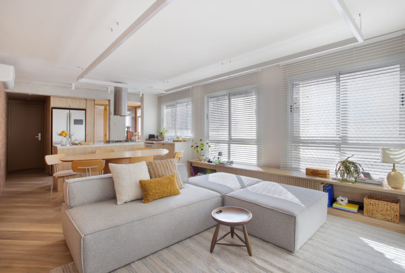 sala de estar com sofá, persiana e tapete em tom off-white