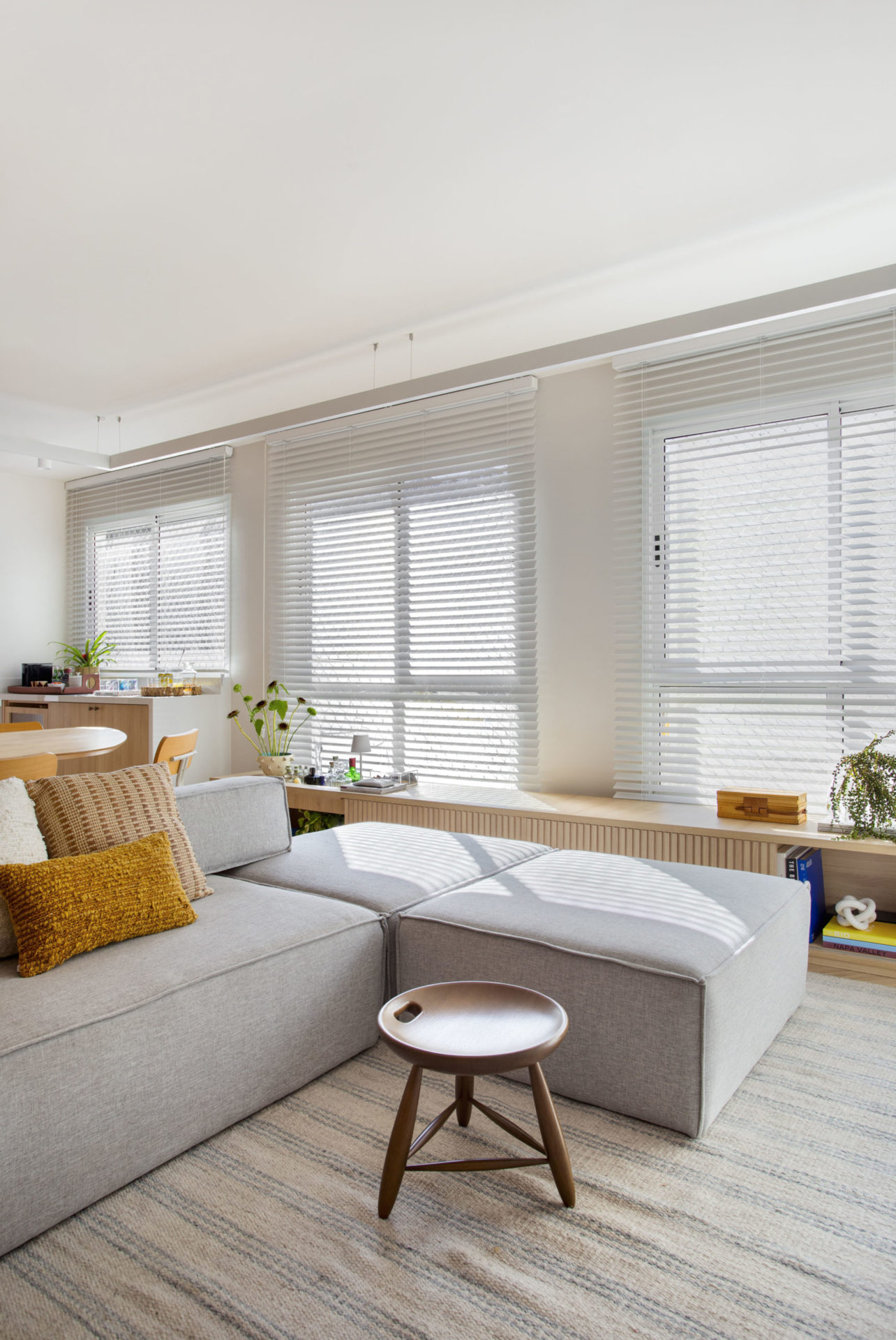 sala de estar com tapete off-white, sofá e janela com persiana branca