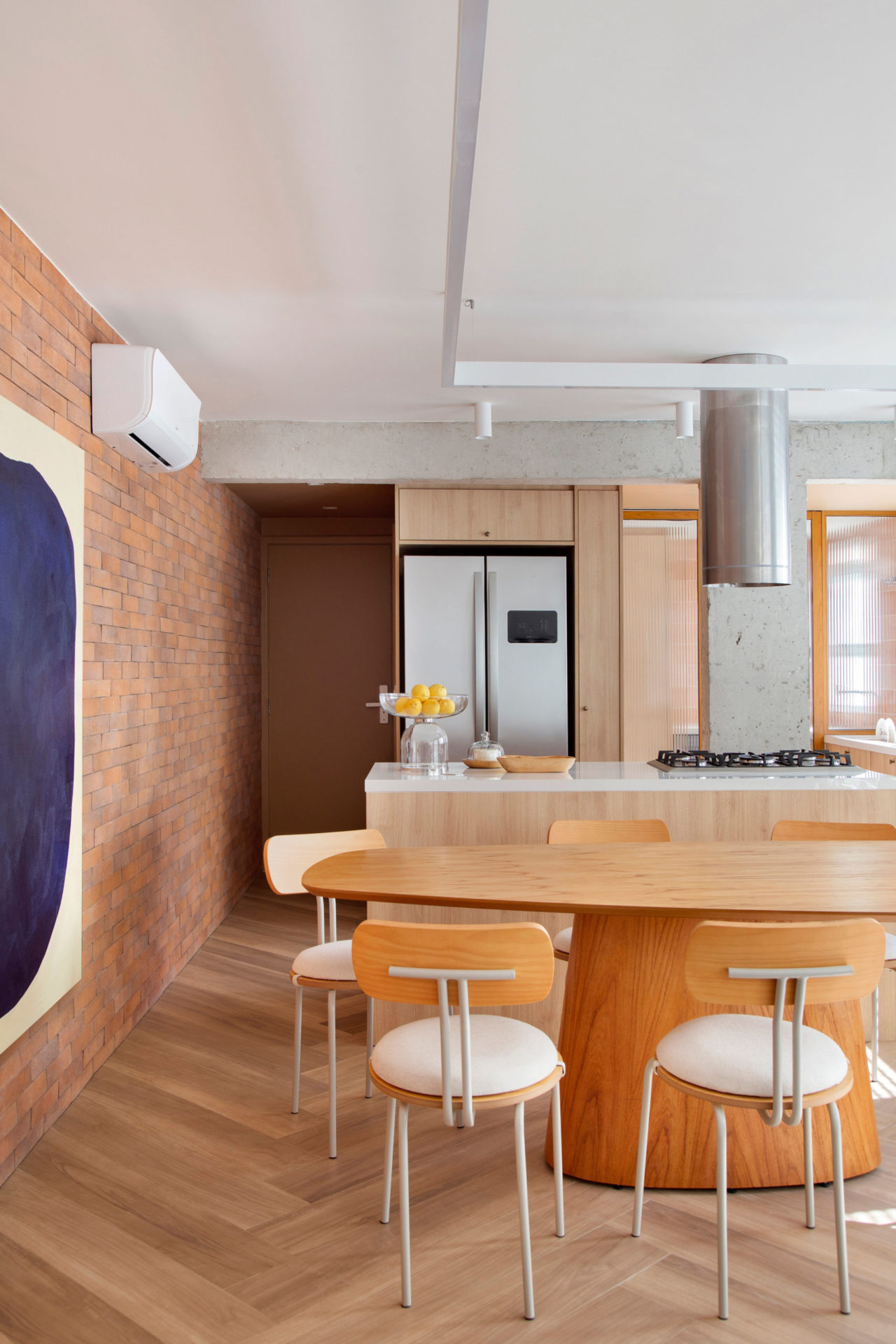 cozinha com bancada em madeira, parede de tijolinhos e grande quadro azul na parede