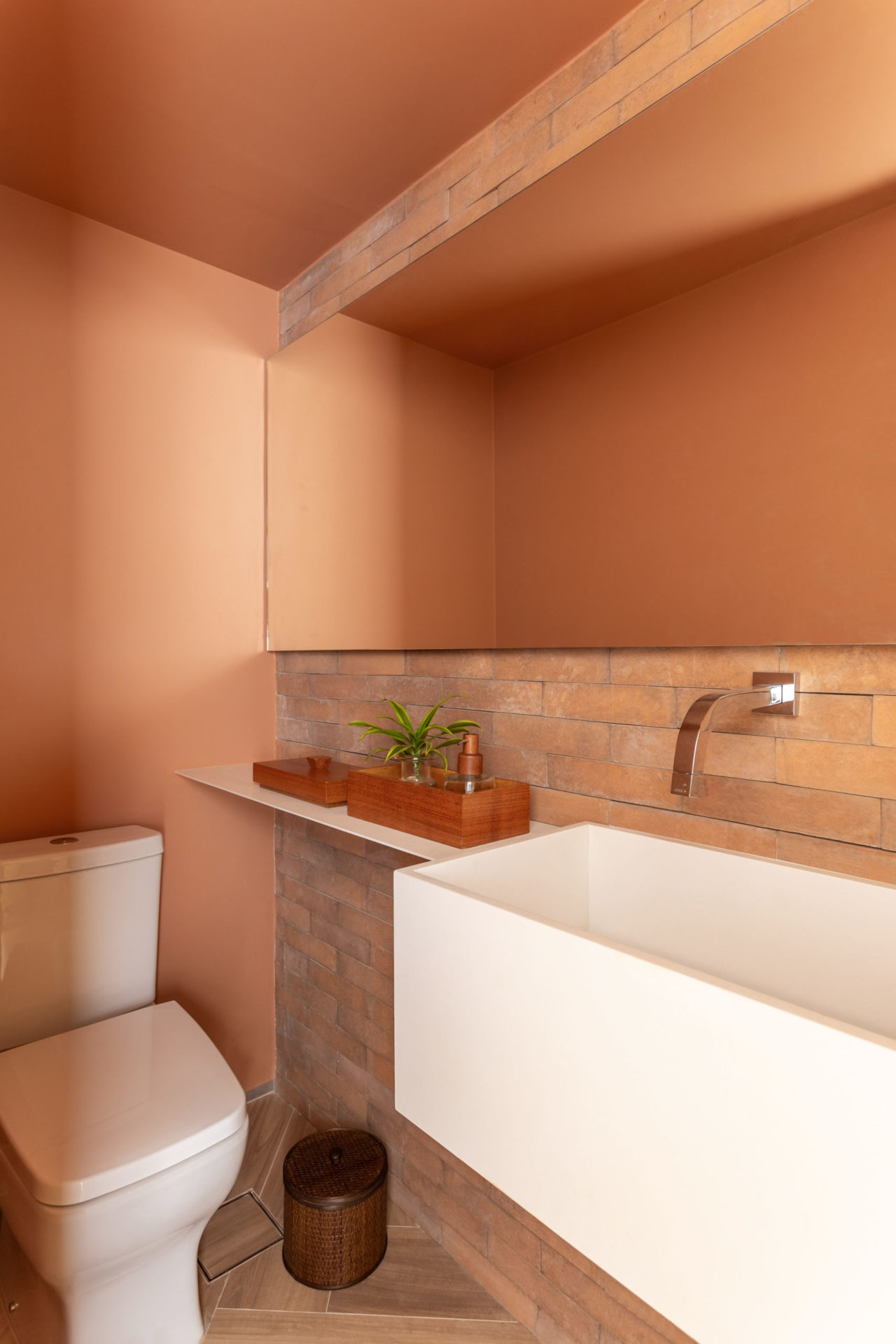 lavabo na cor terracota com pia, espelho e vaso sanitário