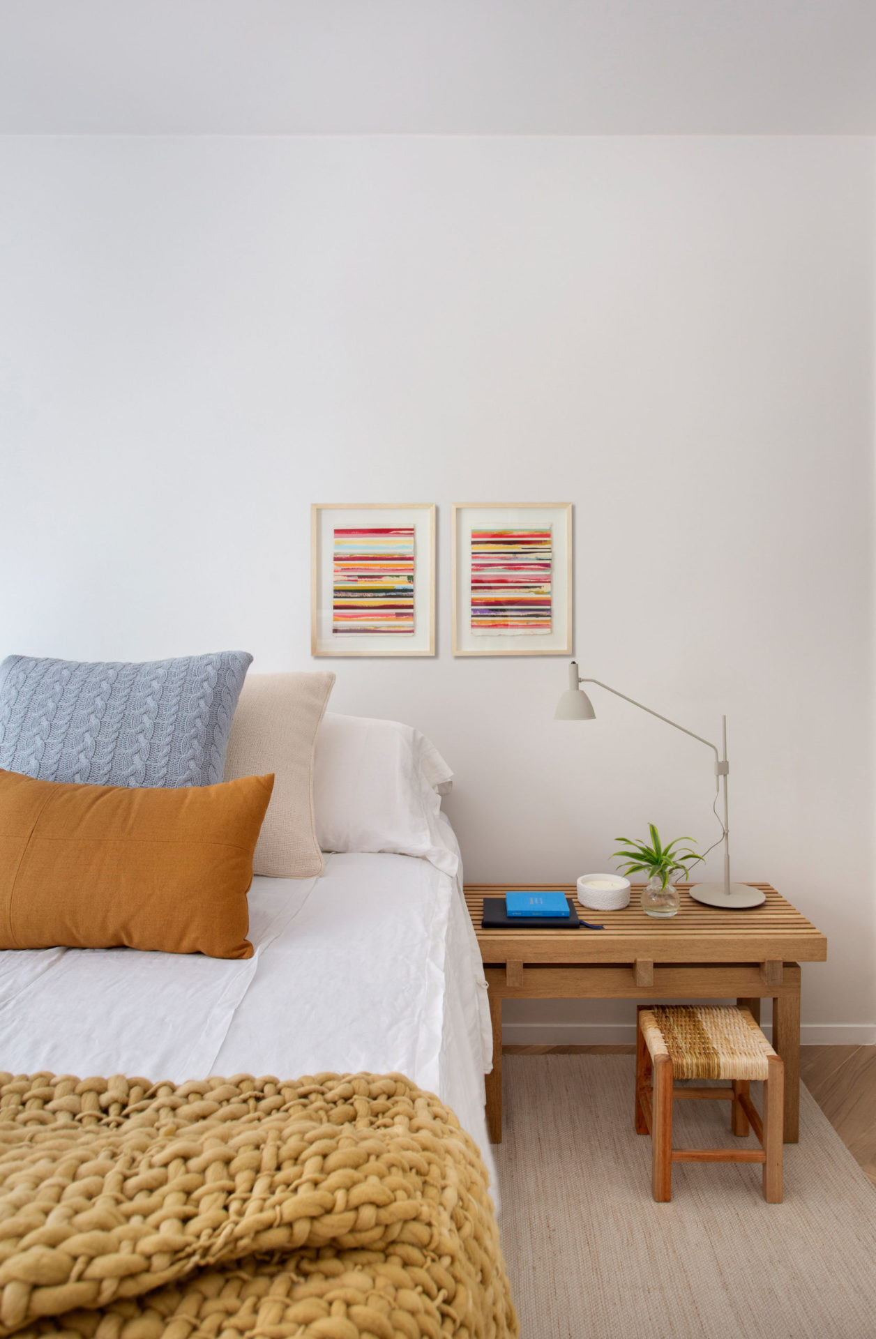 quarto com parede off-white com cama de casal e dois quadros na parede