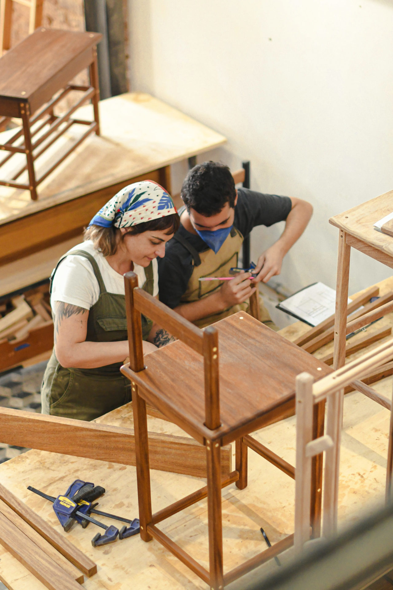uma mulher e um homem trabalhando com marcenaria em um atelier