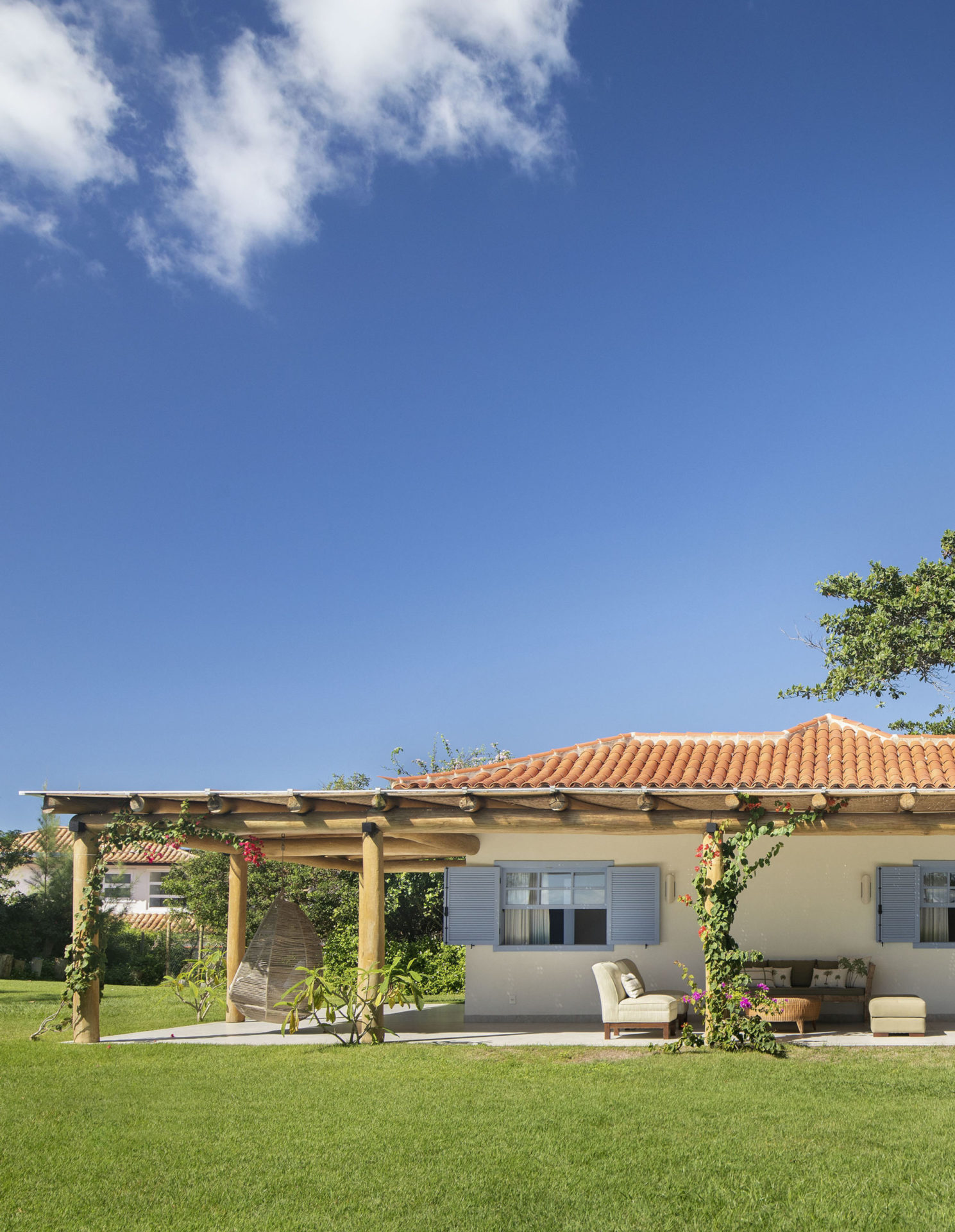 casa de praia com portas e paredes azuis, jardim e céu azul com poucas nuvens