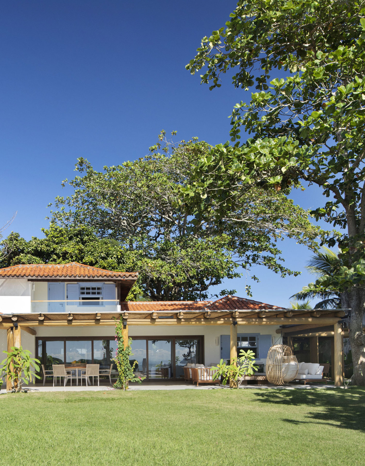 fachada de casa de praia com jardim e árvores