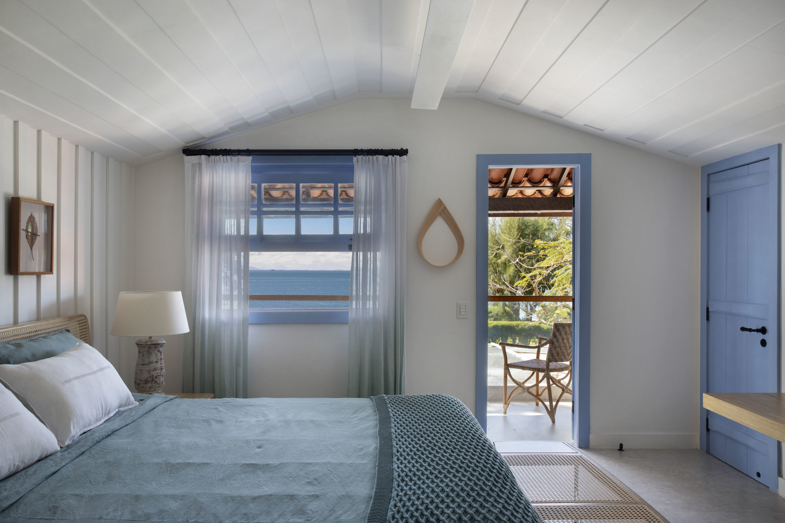 quarto com camas de casal, espelho na parede, janela e porta abertas