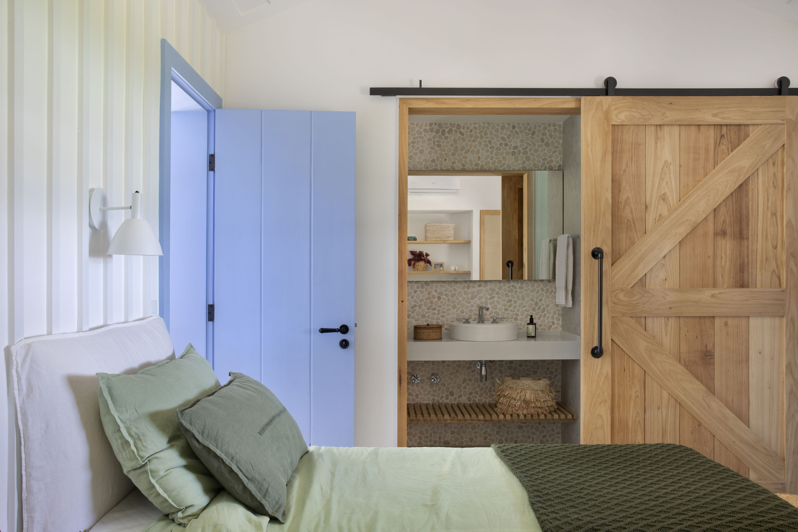 suíte com cama e porta do banheiro em madeira