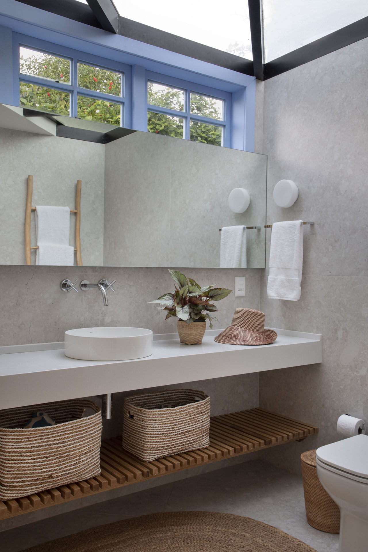 banheiro em tons de azul, branco com cestos de palha em baixo da bancada