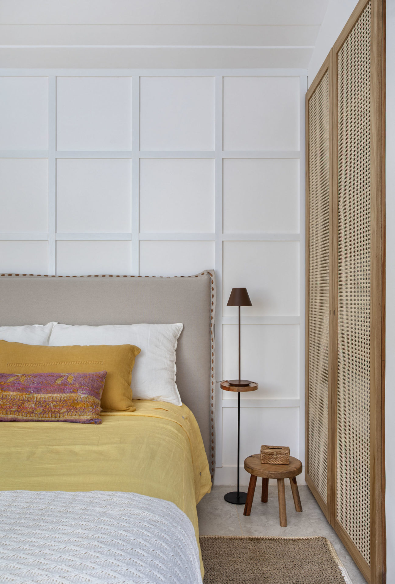 quarto com cama de casal com colcha amarela, porta de madeira