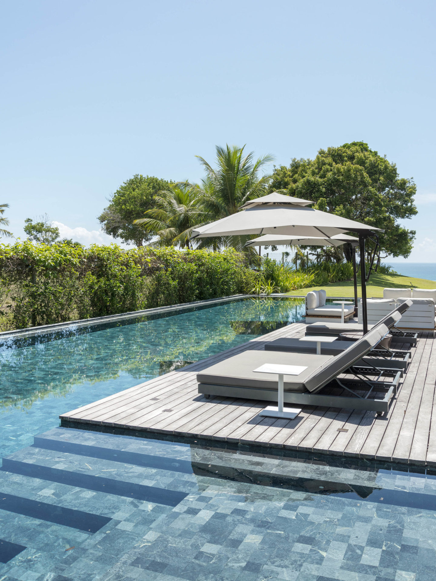 deck de piscina com cadeiras e ombrelones